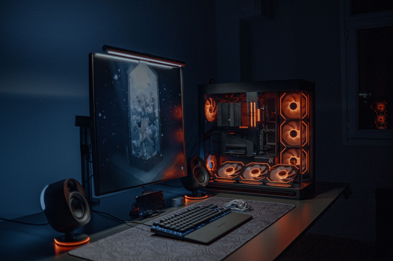 A gaming desk with a glowing PC and a monitor.