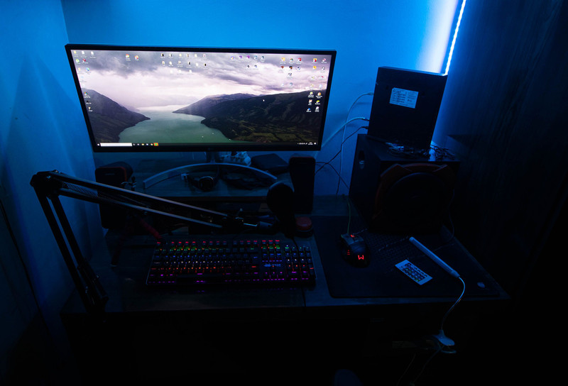 A dark desk with three glowing monitors.
